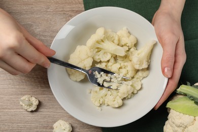 Photo of Woman making cauliflower puree at light wooden table, top view. Baby food