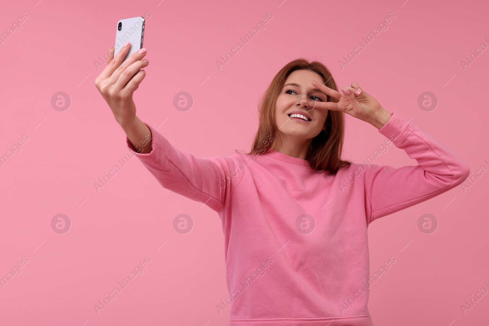 Photo of Beautiful woman taking selfie on pink background