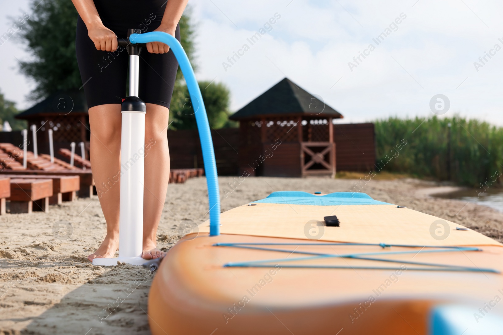 Photo of Woman pumping up SUP board on river shore, closeup