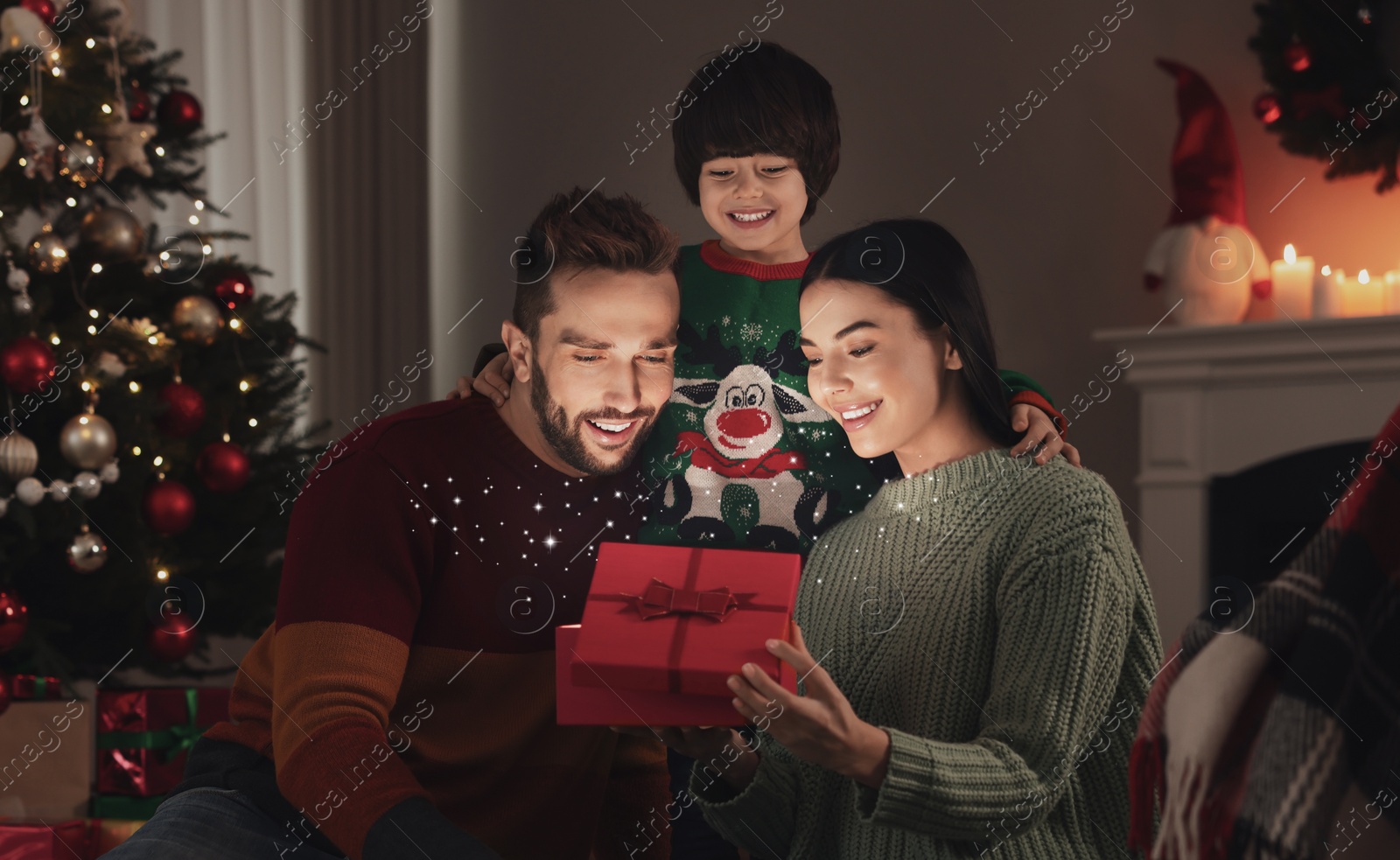 Image of Happy family opening gift box with magical light at home. Christmas celebration