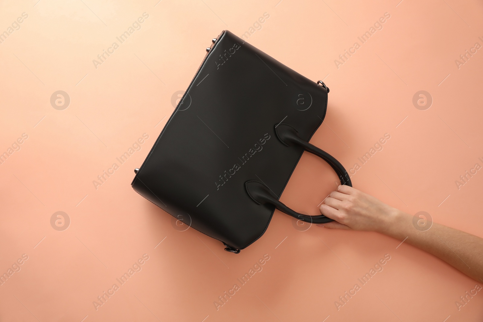 Photo of Woman holding stylish bag on beige background, closeup