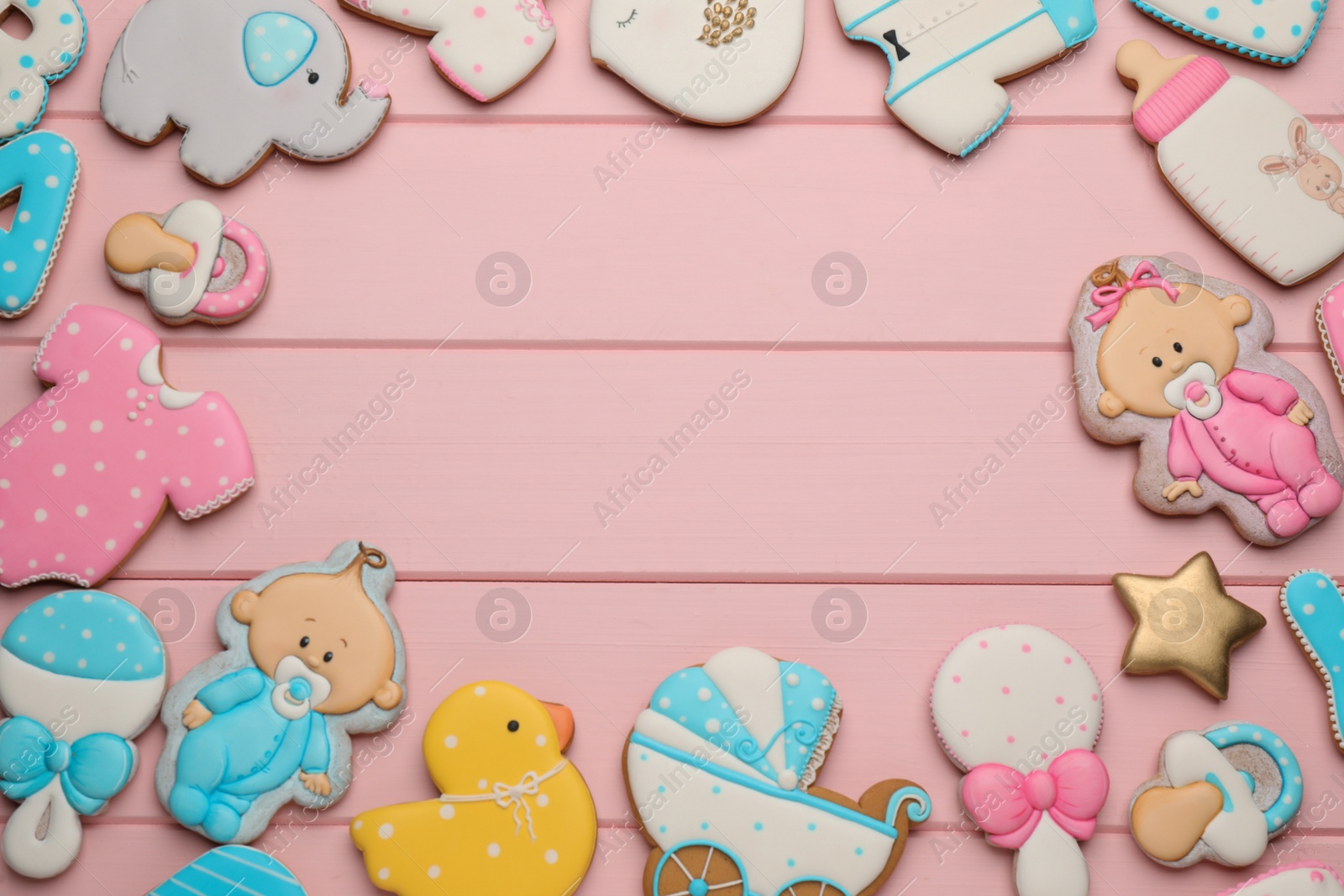 Photo of Frame of baby shower cookies on pink wooden table, flat lay. Space for text