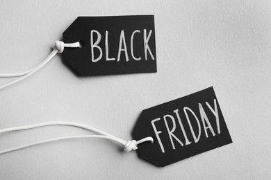 Photo of Tags with words BLACK FRIDAY on light background, top view