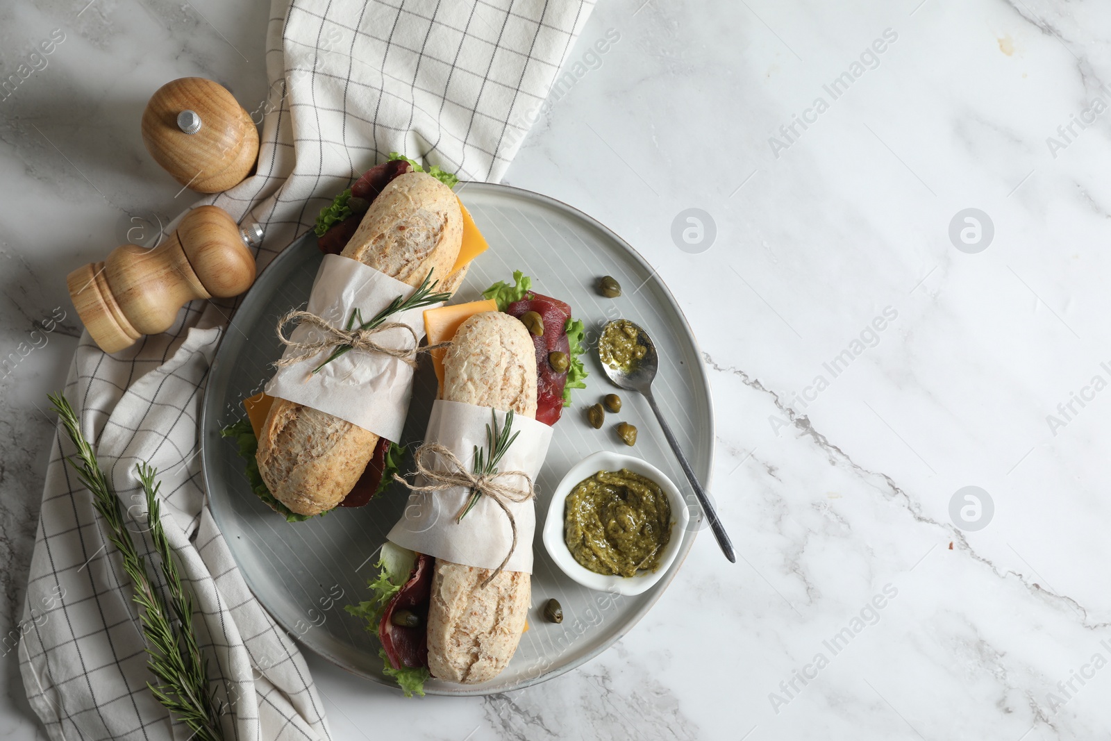 Photo of Delicious sandwiches with bresaola, cheese and lettuce served on white marble table, flat lay. Space for text