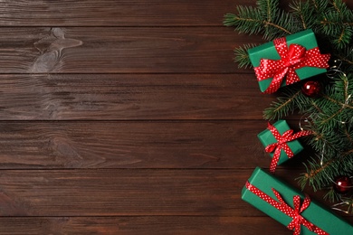 Photo of Gift boxes, Christmas balls and fir branches on wooden background, flat lay. Space for text