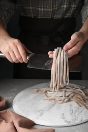 Woman making soba (buckwheat noodles) at grey table, closeup