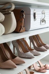 Stylish women's shoes, clothes and bags on shelving unit