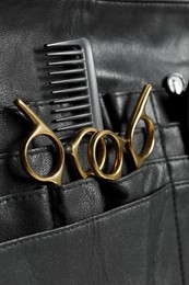 Photo of Hairdresser tools. Professional scissors and comb in leather organizer, closeup