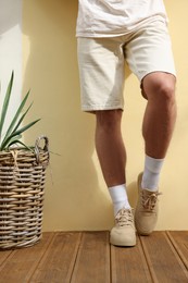 Man wearing stylish sneakers near beige wall, closeup