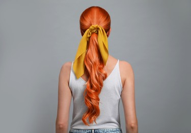Beautiful woman with long orange hair on light grey background, back view