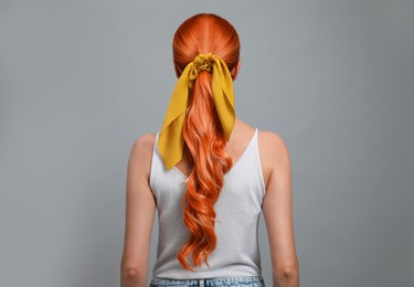 Image of Beautiful woman with long orange hair on light grey background, back view