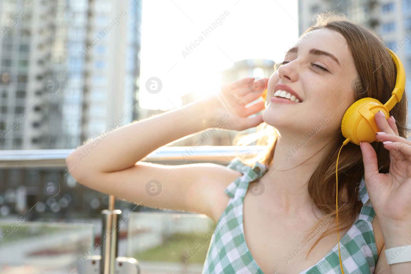 Photo of Beautiful young woman listening to music with headphones on sunny day outdoors