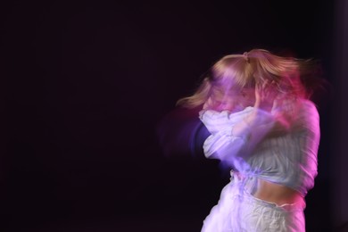 Photo of Young woman performing contemporary dance on black background, motion blur effect. Space for text