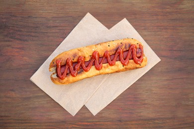 Fresh tasty hot dog with ketchup on wooden table, top view