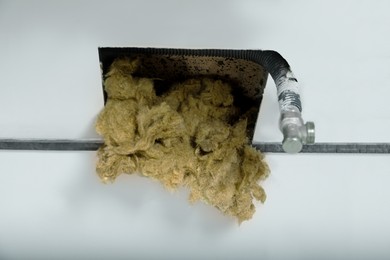 Photo of Hole in wall with metal pipe and thermal insulation material, closeup