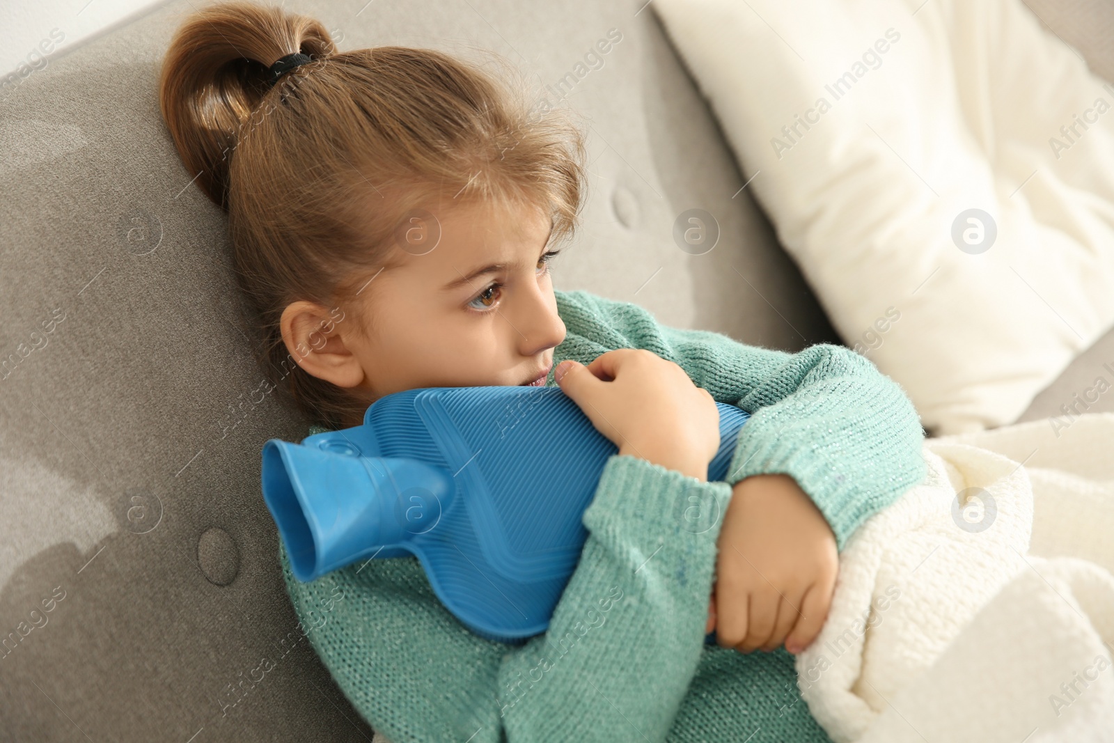 Photo of Ill girl with hot water bottle suffering from cold at home