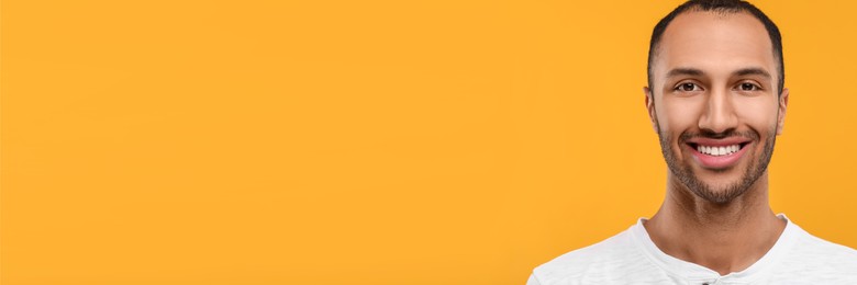 Image of Man with clean teeth smiling on orange background, space for text. Banner design