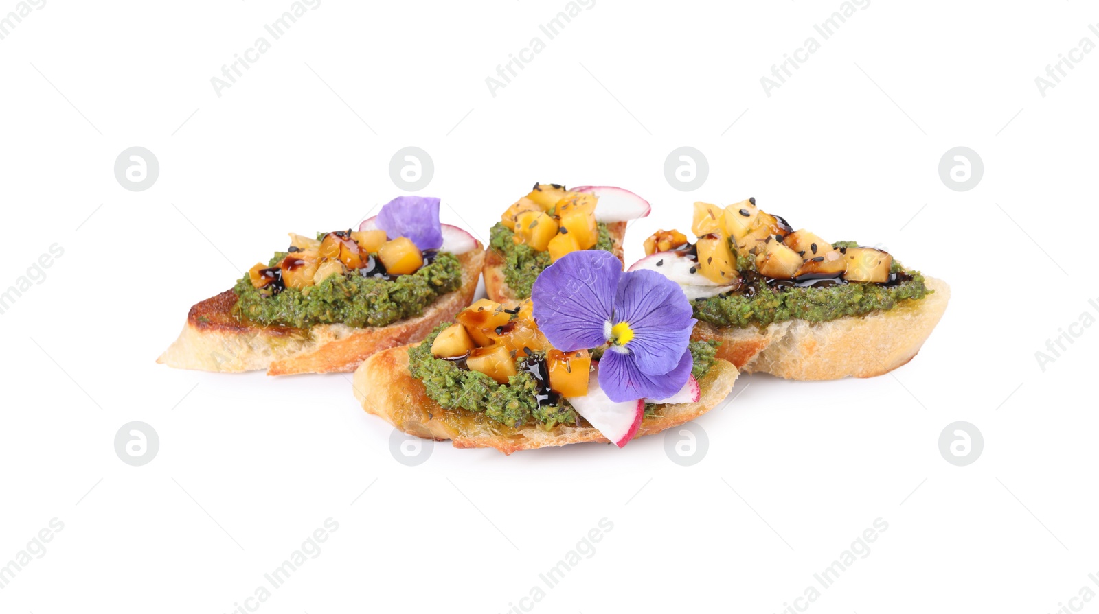 Photo of Delicious bruschettas with pesto sauce, tomatoes, balsamic vinegar and violet flower isolated on white