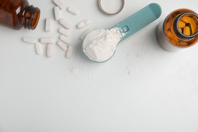 Photo of Measuring scoop of amino acids powder and pills on white table, flat lay. Space for text