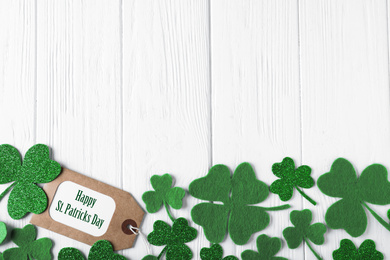 Photo of Flat lay composition with clover leaves on white wooden table, space for text. St. Patrick's Day celebration