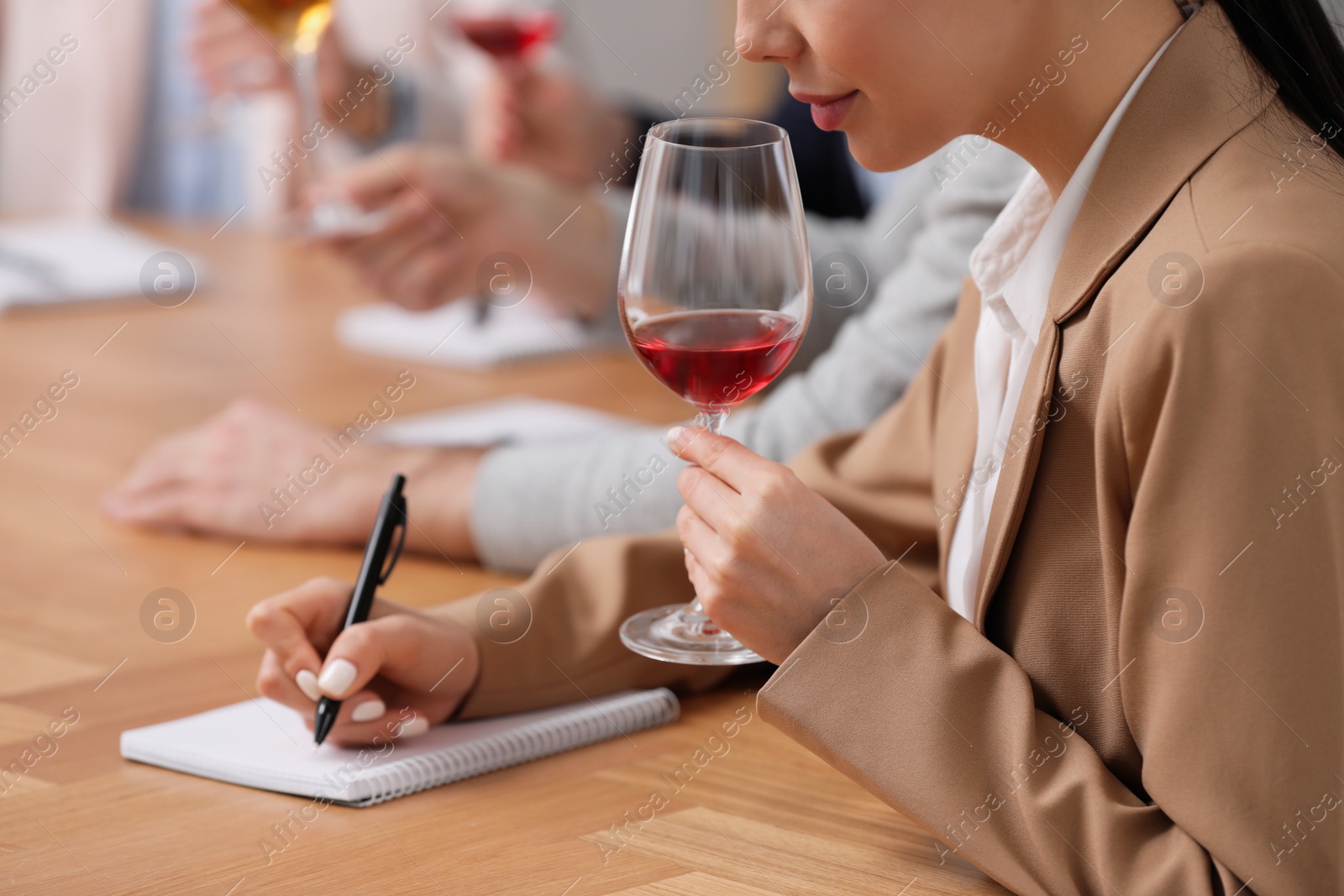 Photo of Sommeliers tasting different sorts of wine at table indoors, closeup