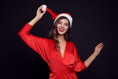 Photo of Happy woman in Santa hat on black background. Christmas party