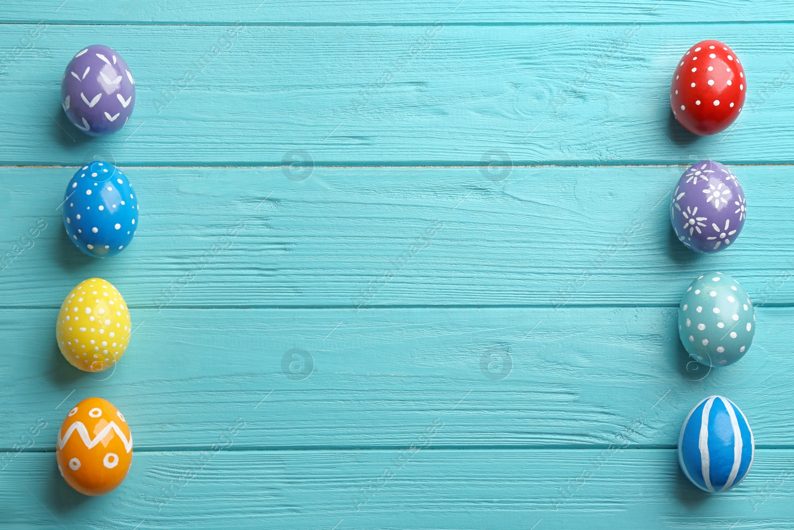 Photo of Flat lay composition of painted Easter eggs on wooden table, space for text