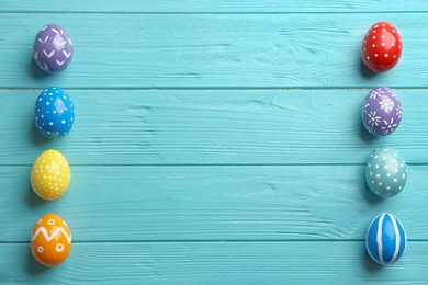 Flat lay composition of painted Easter eggs on wooden table, space for text