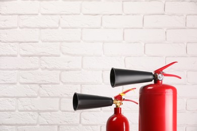 Fire extinguishers against white brick wall. Space for text