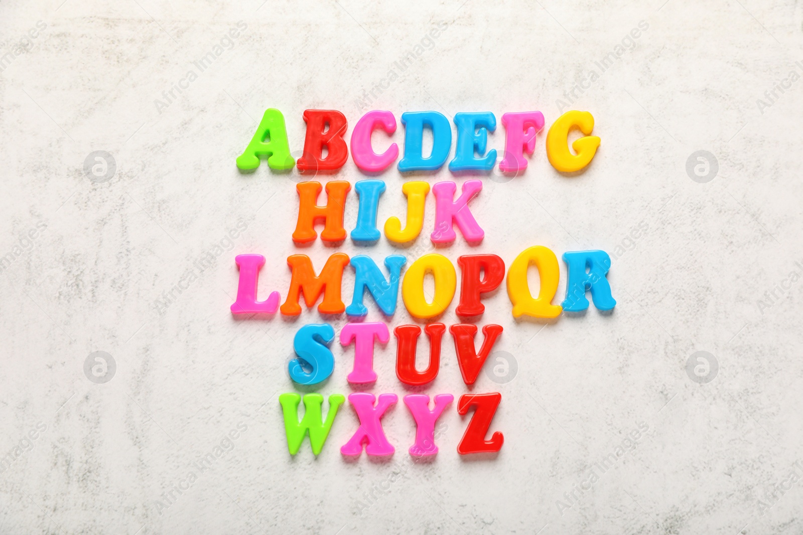 Photo of Colorful magnetic letters on white textured background, flat lay. Alphabetical order