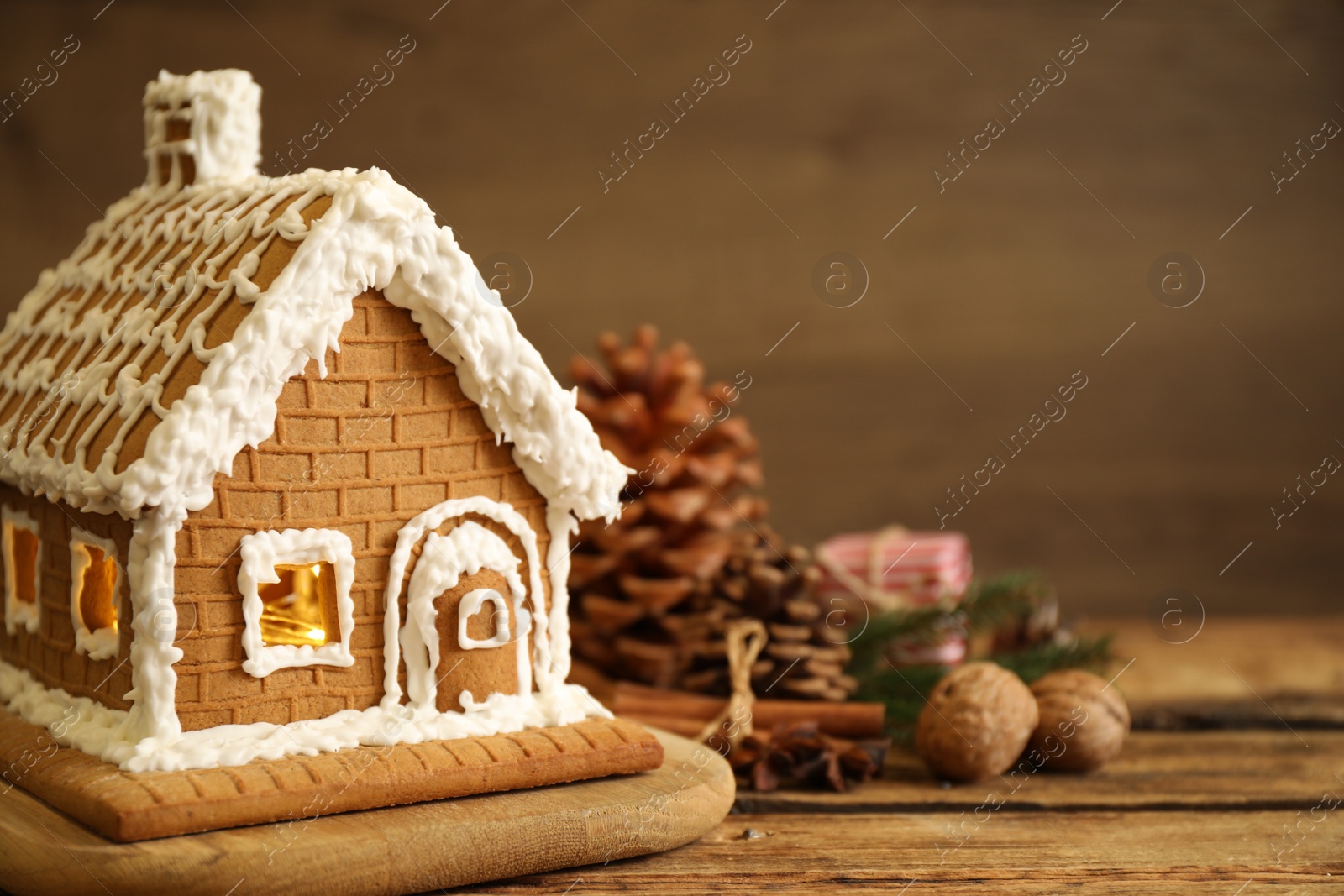 Photo of Beautiful gingerbread house decorated with icing on wooden table, closeup. Space for text