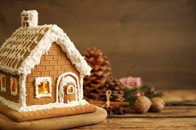 Beautiful gingerbread house decorated with icing on wooden table, closeup. Space for text