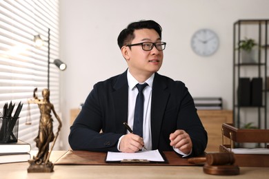 Notary writing notes at wooden table in office