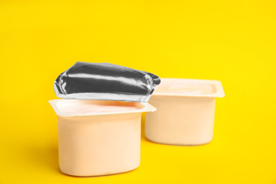 Photo of Tasty organic yogurt in plastic cups on yellow background