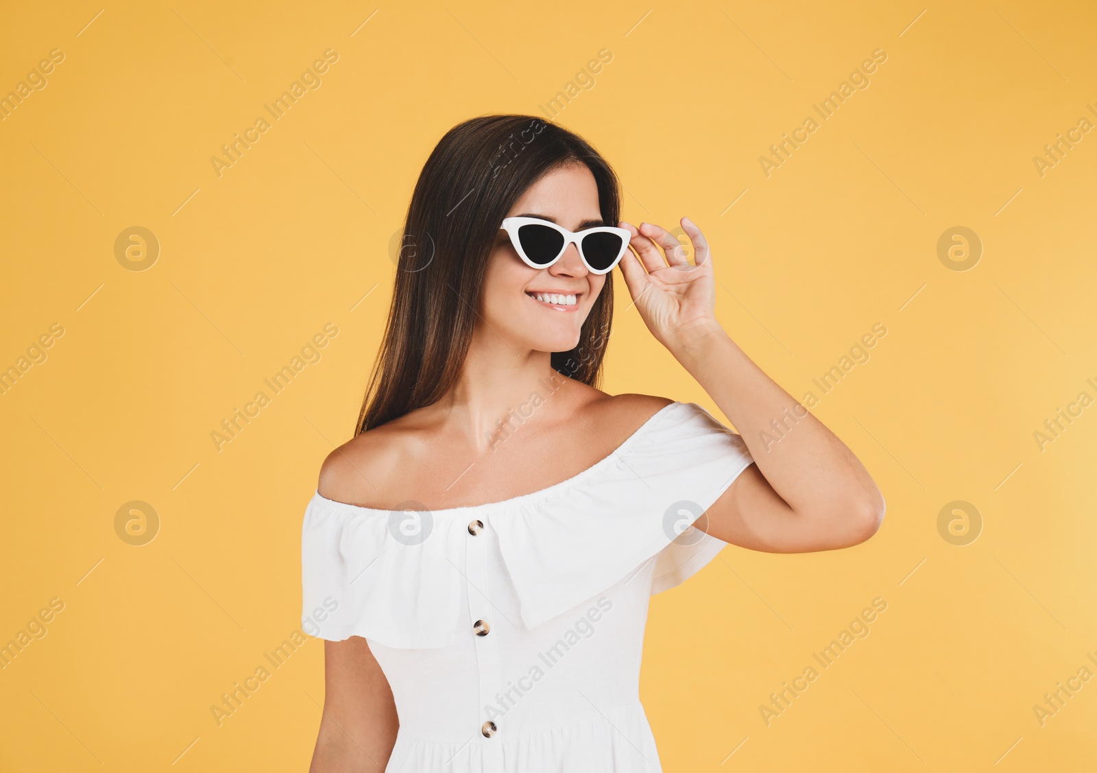 Photo of Young woman wearing stylish white dress on yellow background