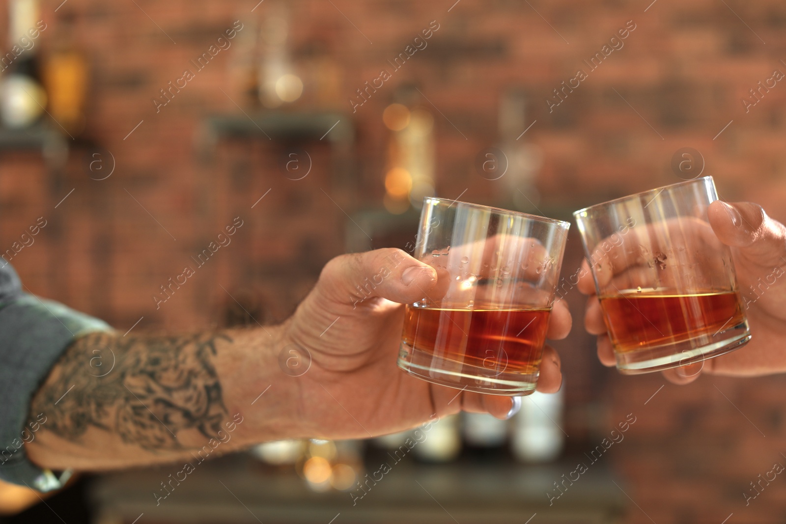 Photo of Friends toasting with glasses of whiskey indoors, closeup