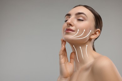 Woman with perfect skin after cosmetic treatment on grey background, space for text. Lifting arrows on her neck and face