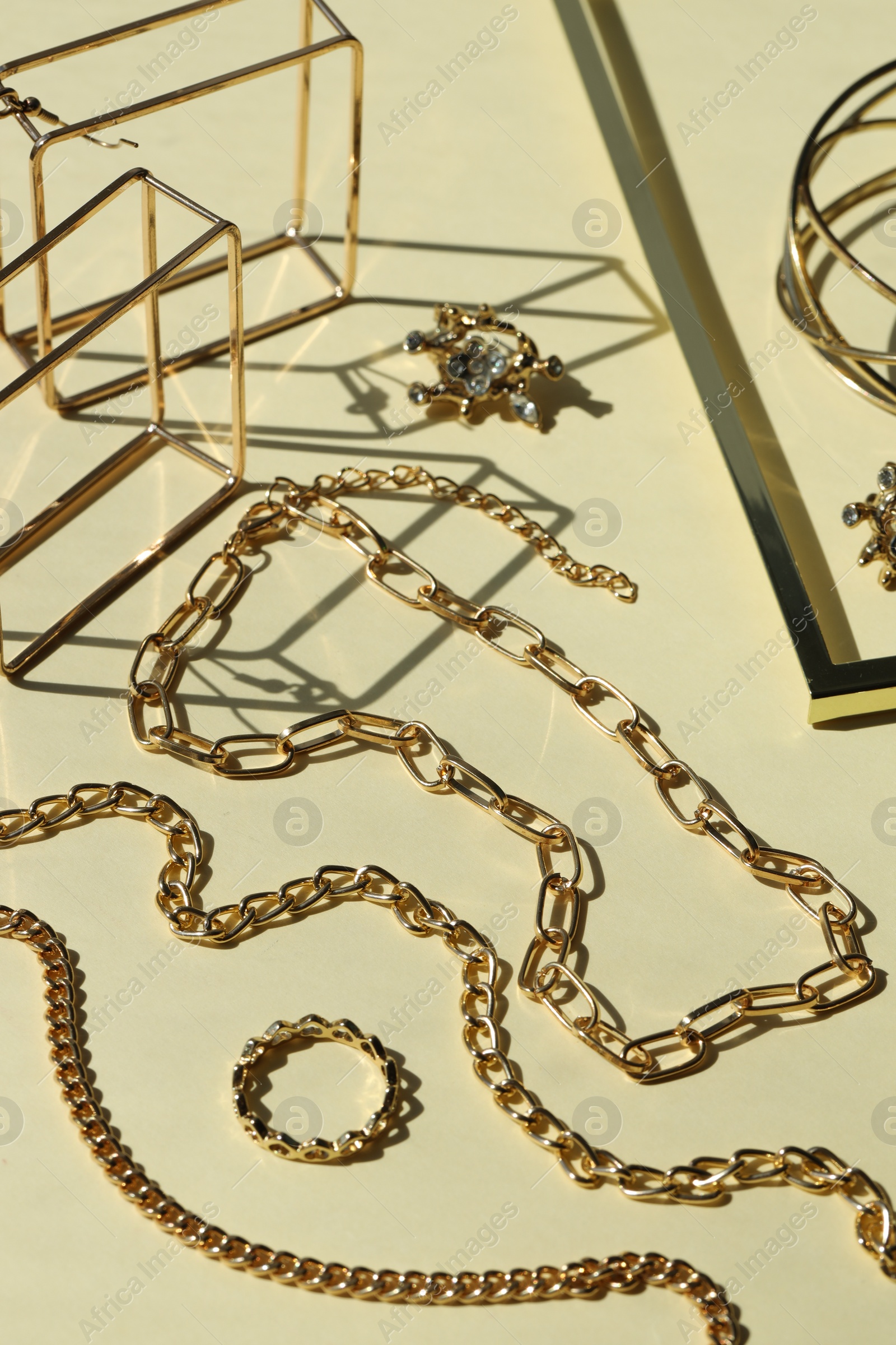 Photo of Metal chains and other different accessories on beige background. Luxury jewelry