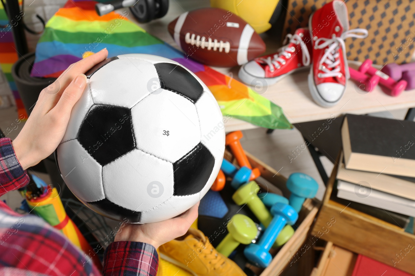 Photo of Woman holding ball near many different stuff indoors, closeup. Garage sale