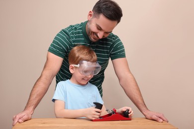 Father teaching son how to work with plane near beige wall
