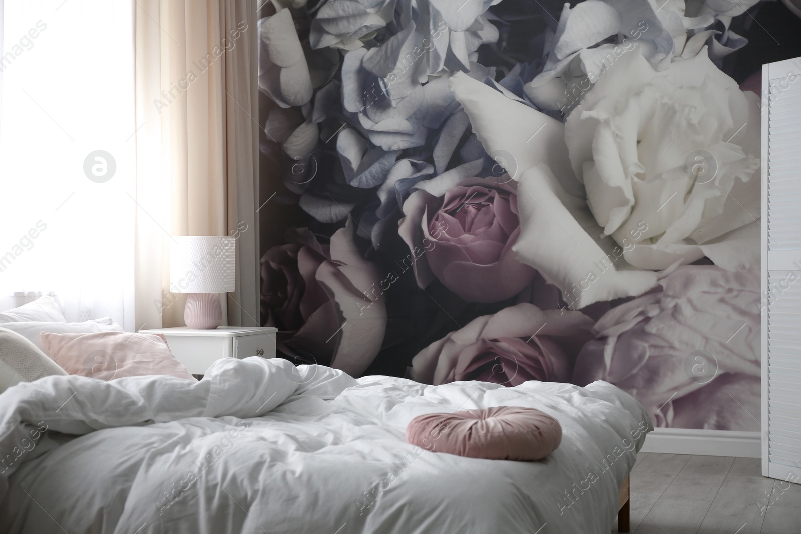 Photo of Comfortable bed near wall with floral wallpaper. Stylish room interior