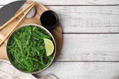 Photo of Tasty seaweed salad in bowl served on wooden table, flat lay. Space for text