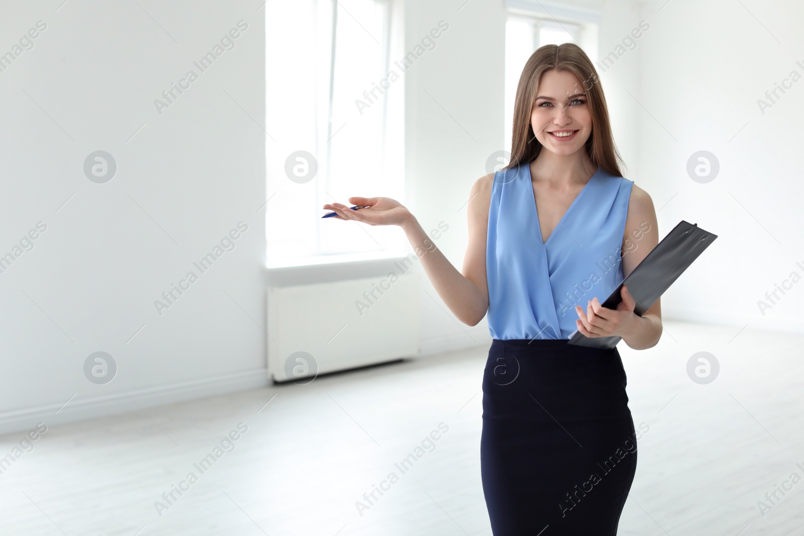 Photo of Beautiful real estate agent with clipboard indoors