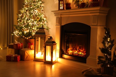 Photo of Beautiful fireplace, Christmas tree and other decorations in living room at night. Interior design