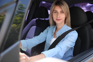 Woman with fastened safety belt on driver's seat in car