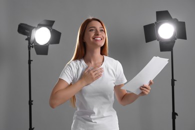 Photo of Casting call. Young woman with script performing on grey background