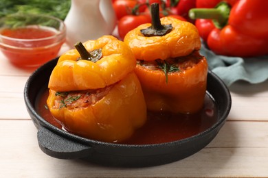 Photo of Tasty stuffed peppers in pan on light wooden table, closeup