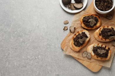 Delicious bruschettas with truffle sauce on light grey table, flat lay. Space for text