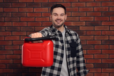 Photo of Man holding red canister against brick wall