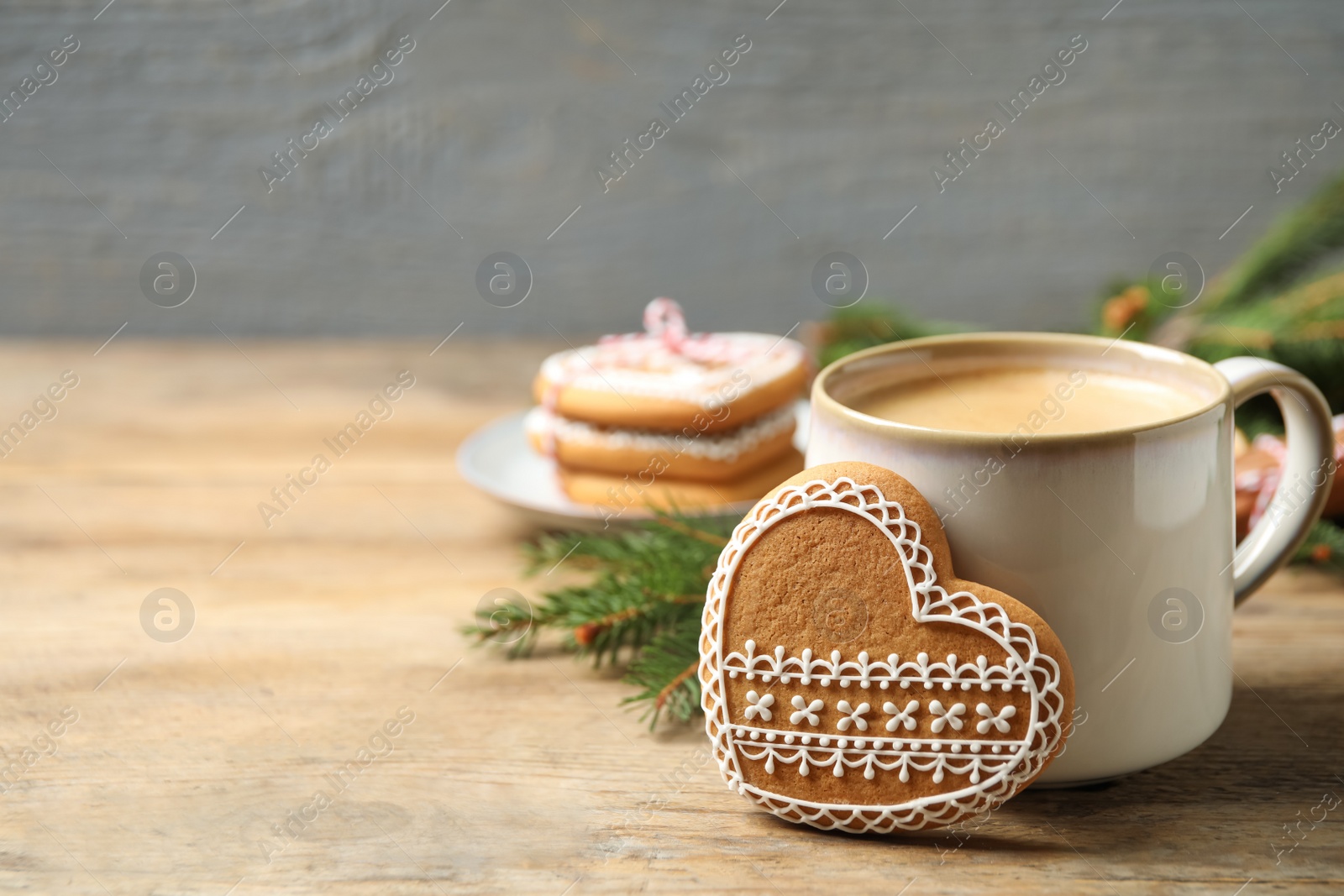 Photo of Tasty heart shaped gingerbread cookie and hot drink on wooden table. Space for text